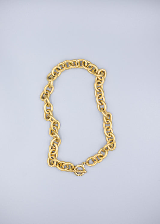 Birds Eye view of a 18k gold plated link chain necklace on a light gray background