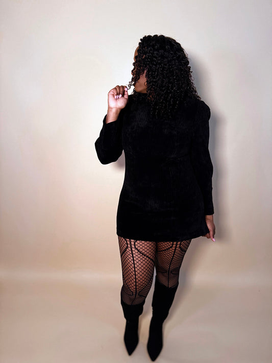 Front view of elegant woman modeling Magnetic Waves Fishnet Tights, hosiery for women, styled with a black dress and boots for a chic, trendy look.