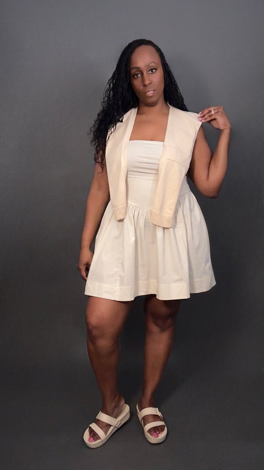 Woman wearing a cream dress with a cream knitted shawl against a dark gray background