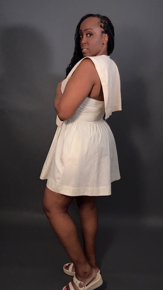 Woman wearing a cream dress with a matching cream knitted shawl against a dark background