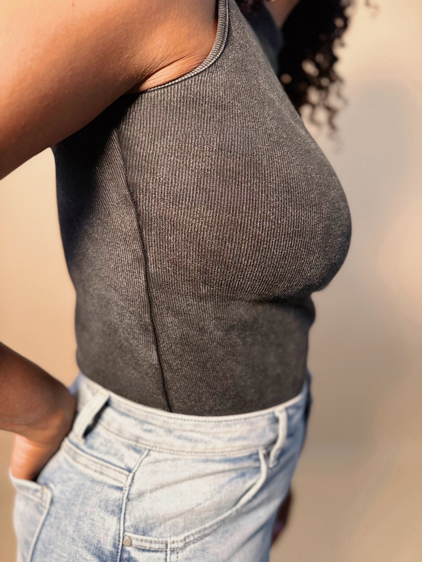 Side detail view of Women's Elevated Casual black Mineral Washed Mock Neck Bodysuit top, highlighting its textured finish, sleek fit, and modern design.