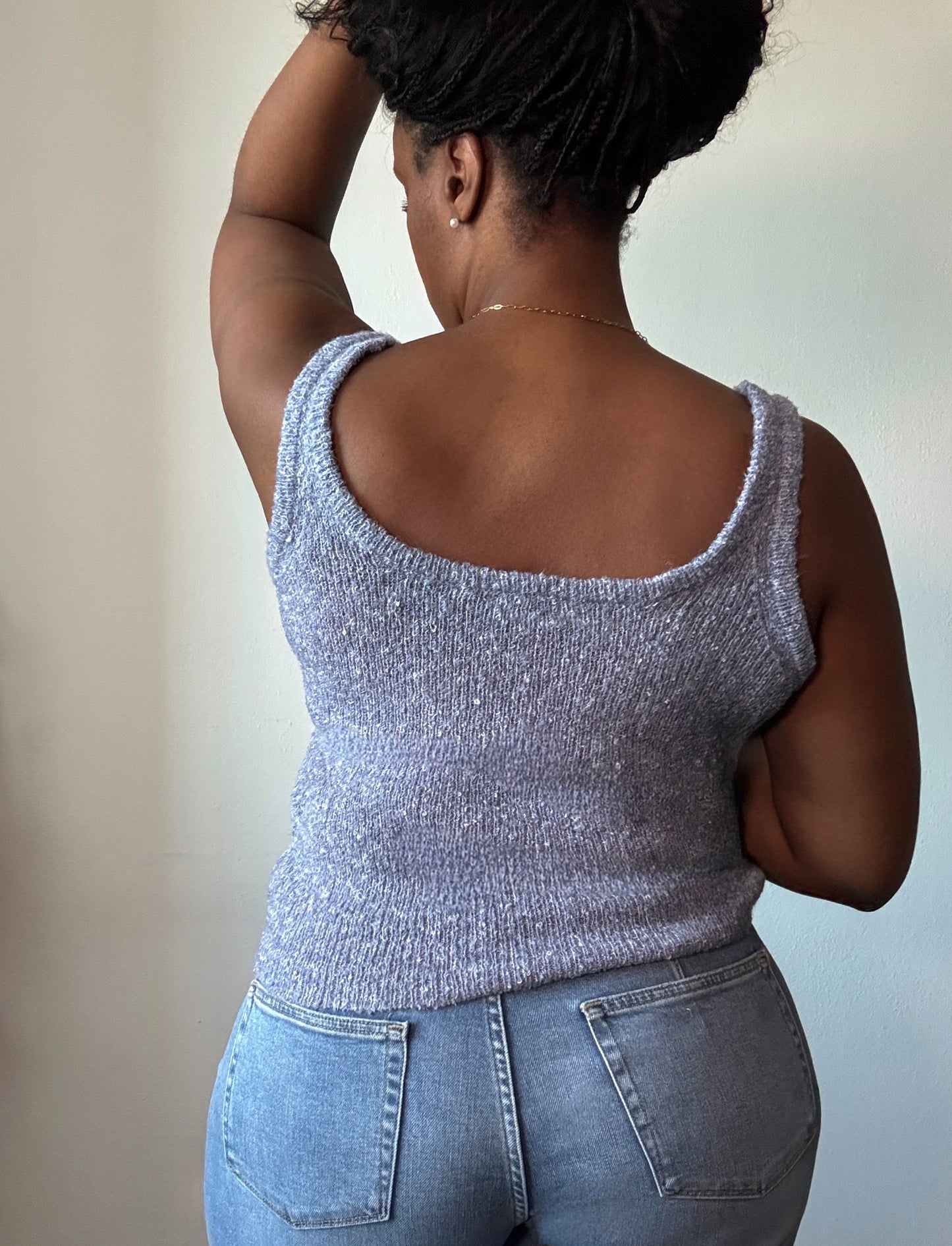 Back view of women's sleeveless solid knit top, highlighting the smooth fabric, seamless design, and comfortable fit for a chic and versatile look.