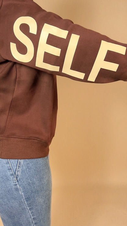BE YOURSELF sweatshirt in brown with 'SELF' text on a beige background
