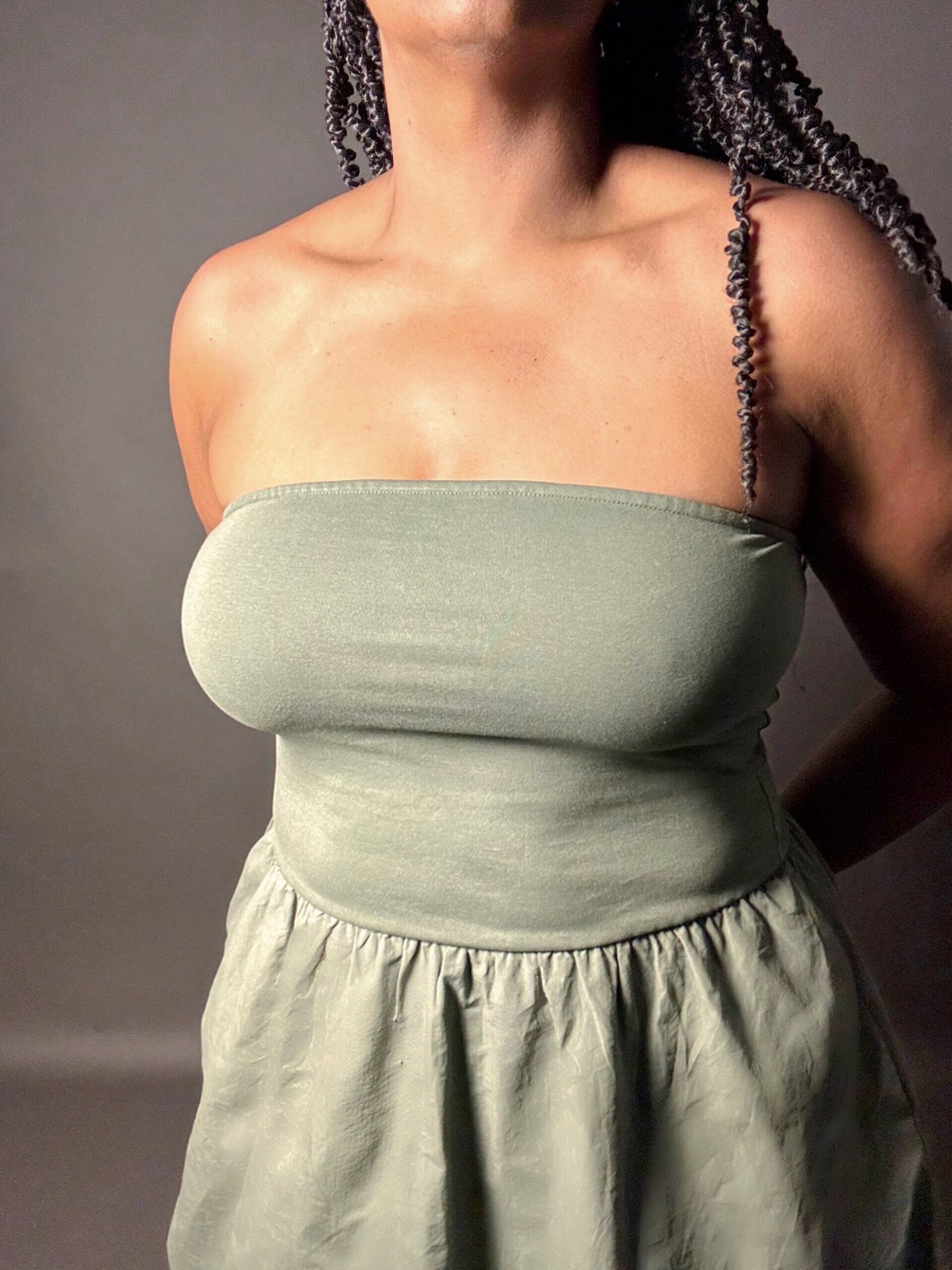 Woman wearing a green strapless dress against a plain gray background zoomed in