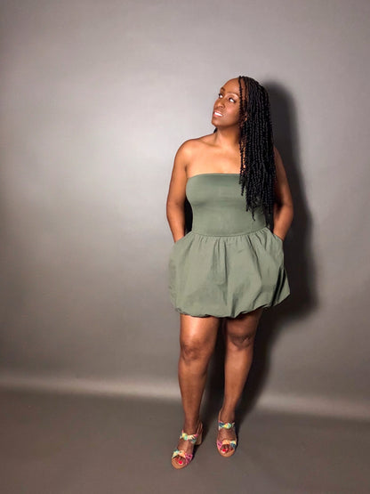 Woman wearing a green strapless dress against a plain gray background