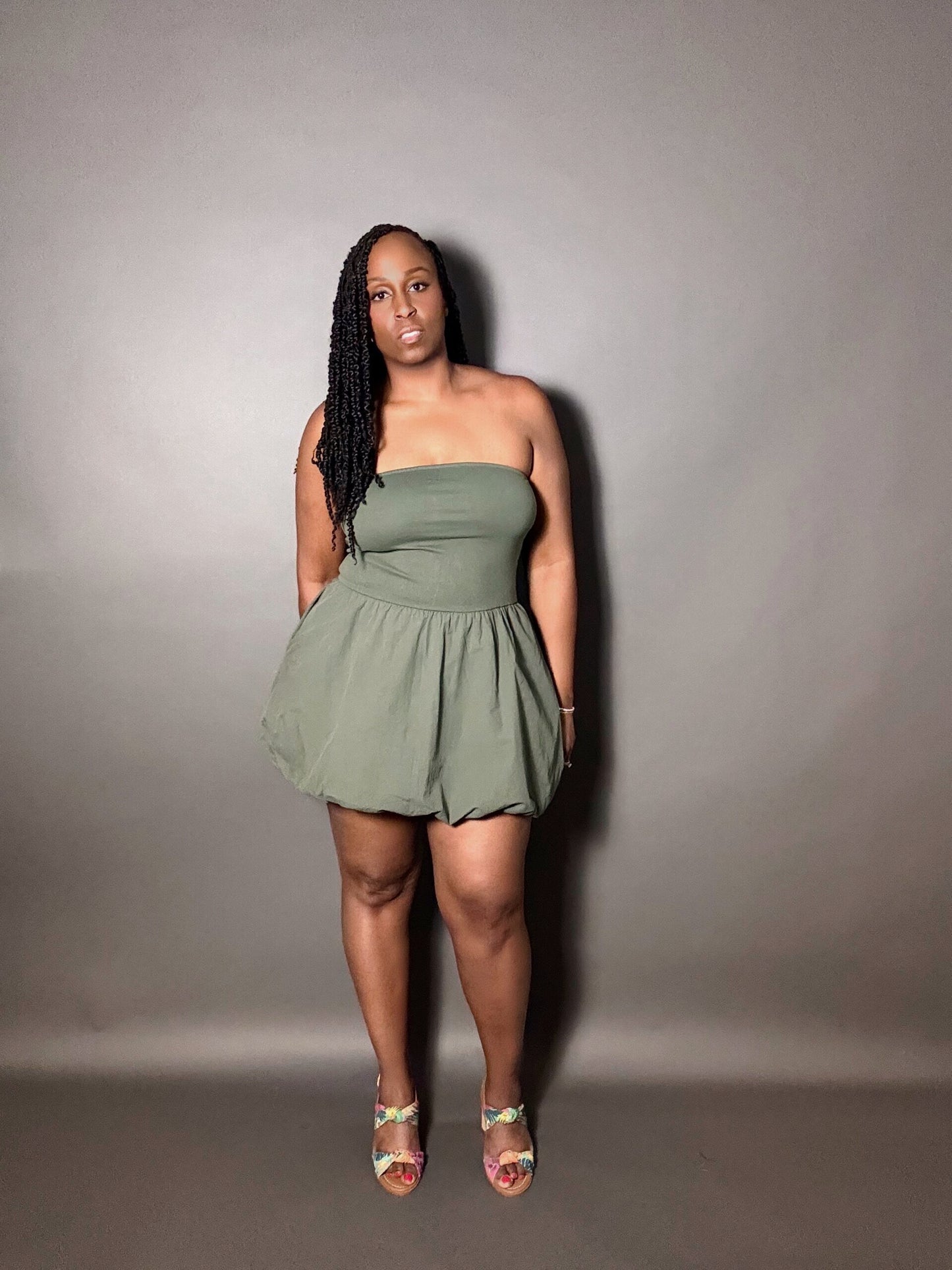 Woman wearing a green strapless dress against a plain gray background
