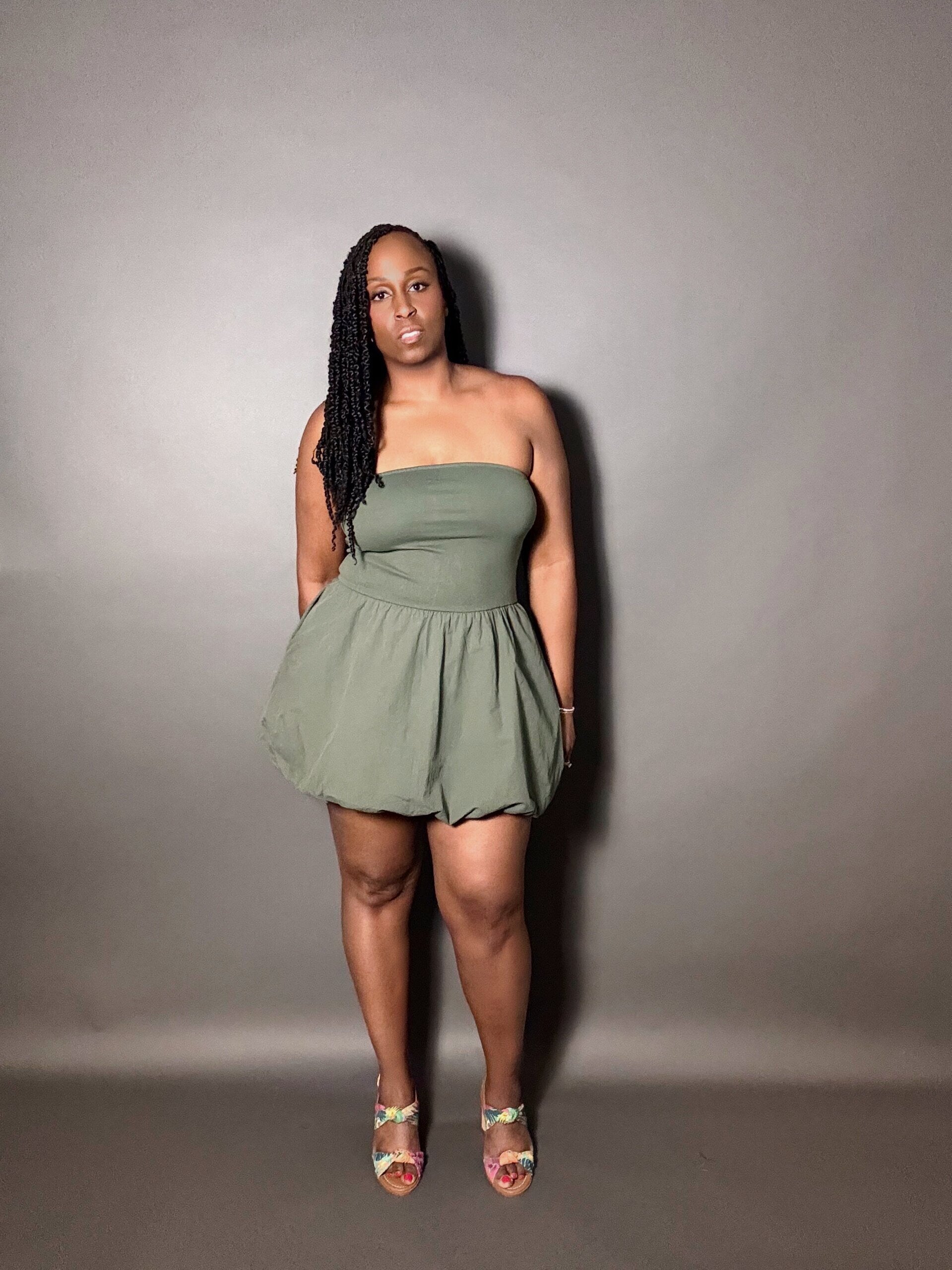 Woman wearing a green strapless dress against a plain gray background