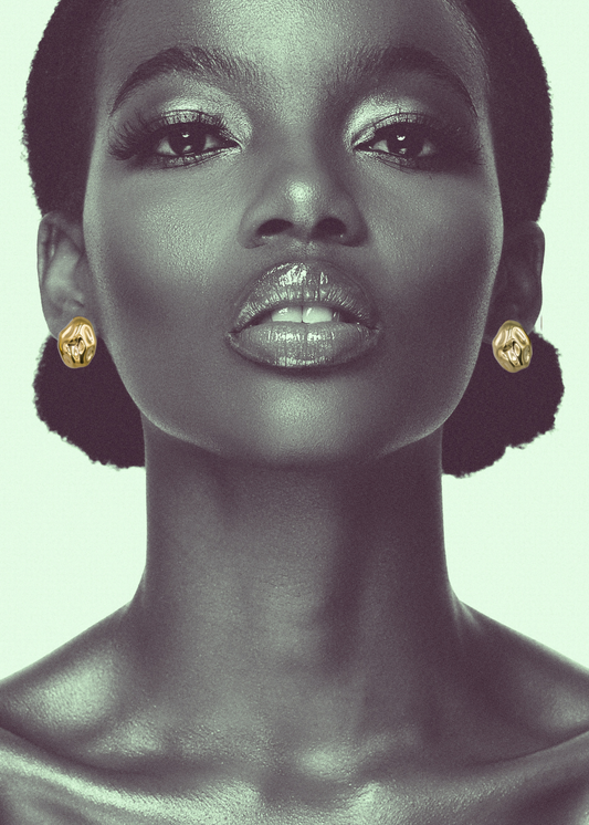 A shot of a woman's neck and head with hammered stud 18k gold plated earrings on a light background