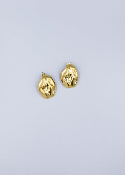 zoomed out pair of 18k gold plated hammered stud earrings laid flat on a light gray background 