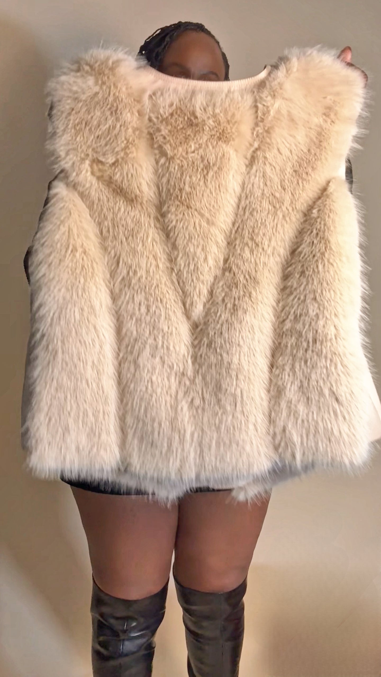 Person wearing a fluffy white vest with a neutral background