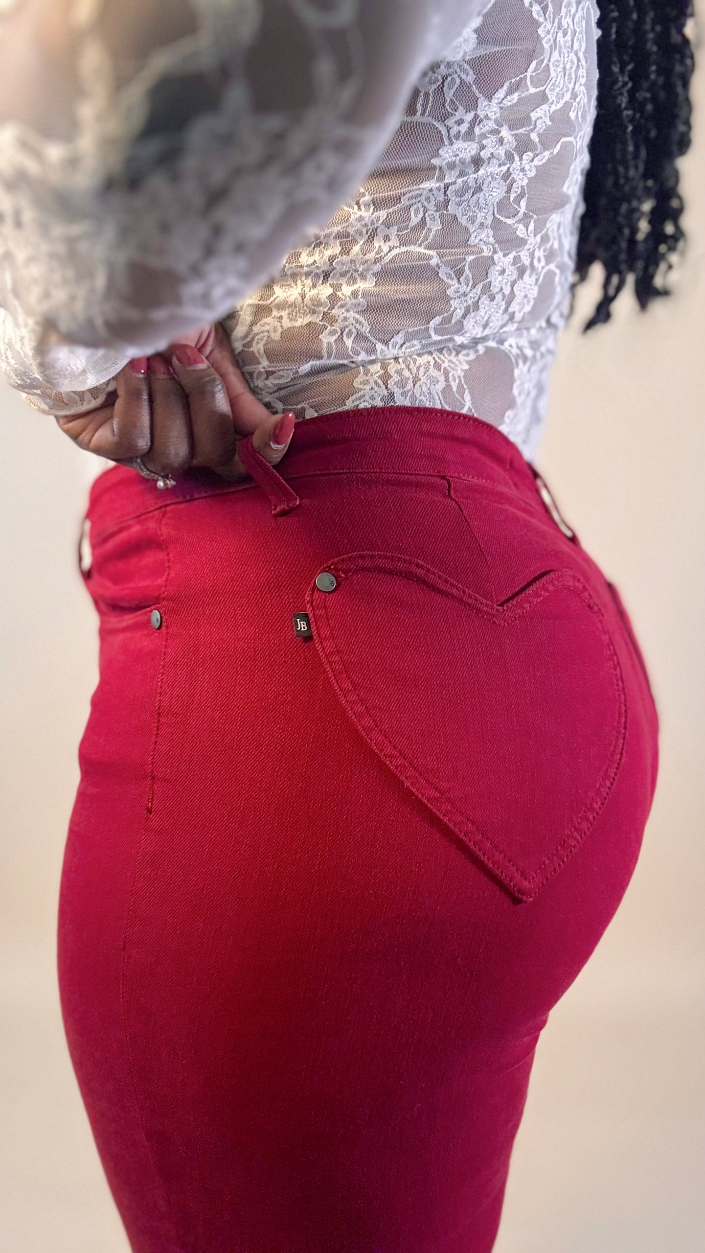 Zoomed in red jeans with heart pocket with a lace top on a neutral background