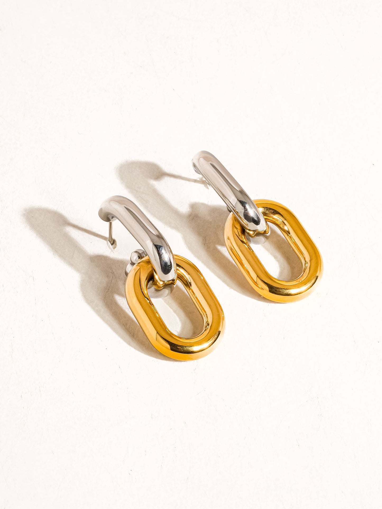 Pair of white and yellow gold chain link hoop earrings on a white background