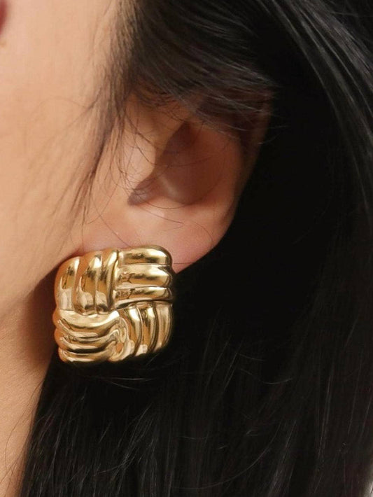Gold woven knit earrings worn by a person with dark hair.