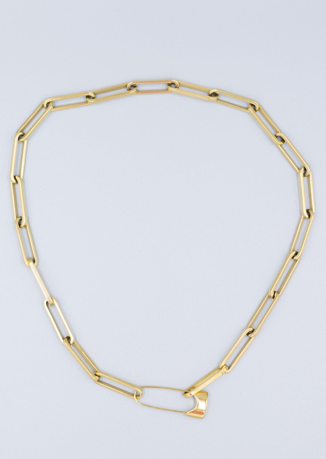 Birds Eye view of a 18k gold plated paperclip link necklace with a Paperclip lock closure laid flat against a light gray background